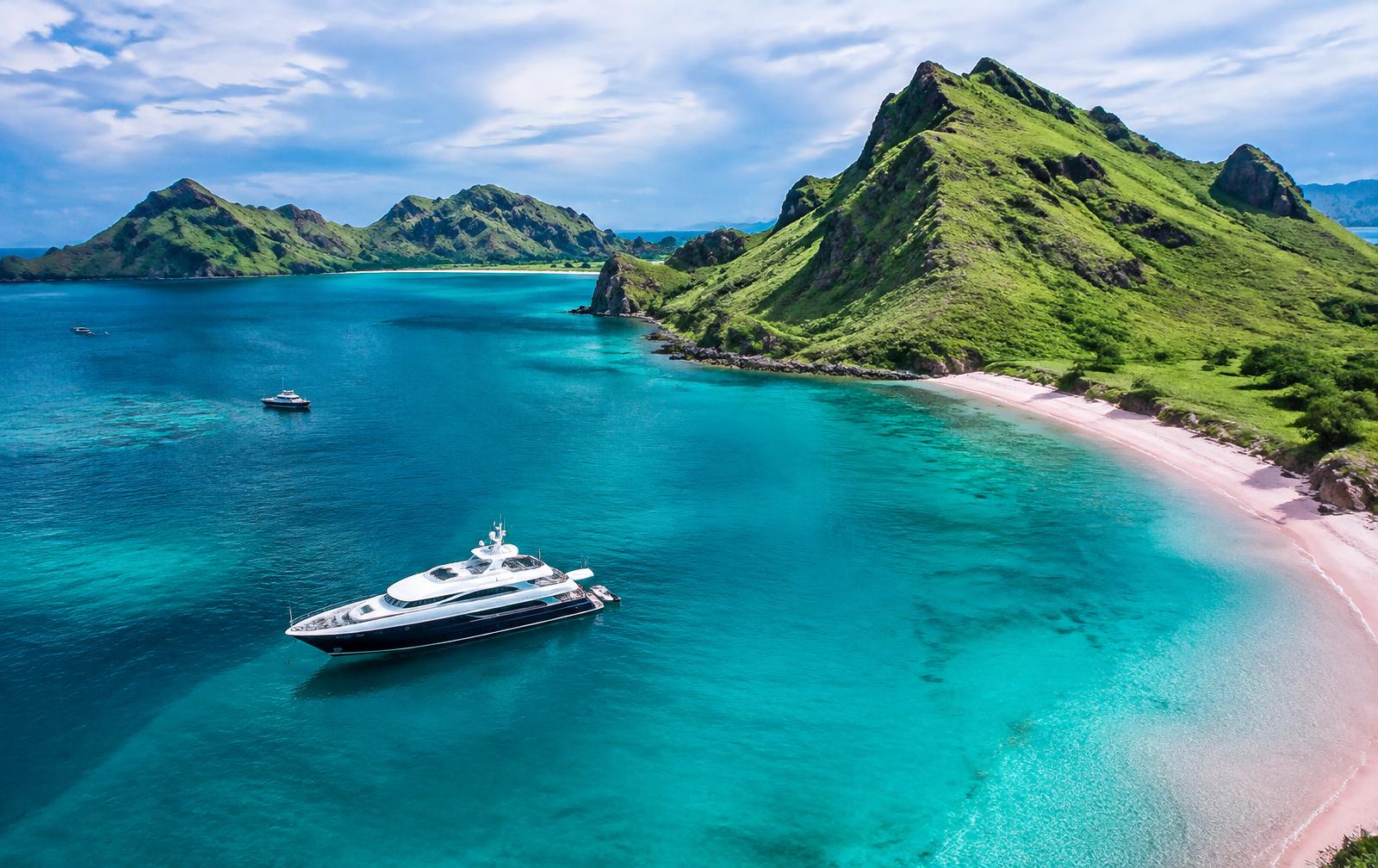 Motor yacht anchored off a pink sand beach in the Komodo archipelago, Indonesia
